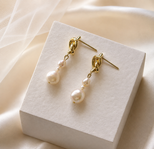 Pair of graduated white freshwater pearl drop earrings with gold-tone knot studs
