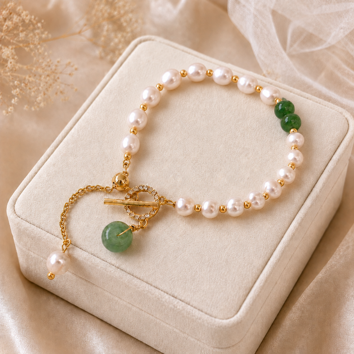 White freshwater pearl bracelet with green bead details and a gold-tone toggle closure