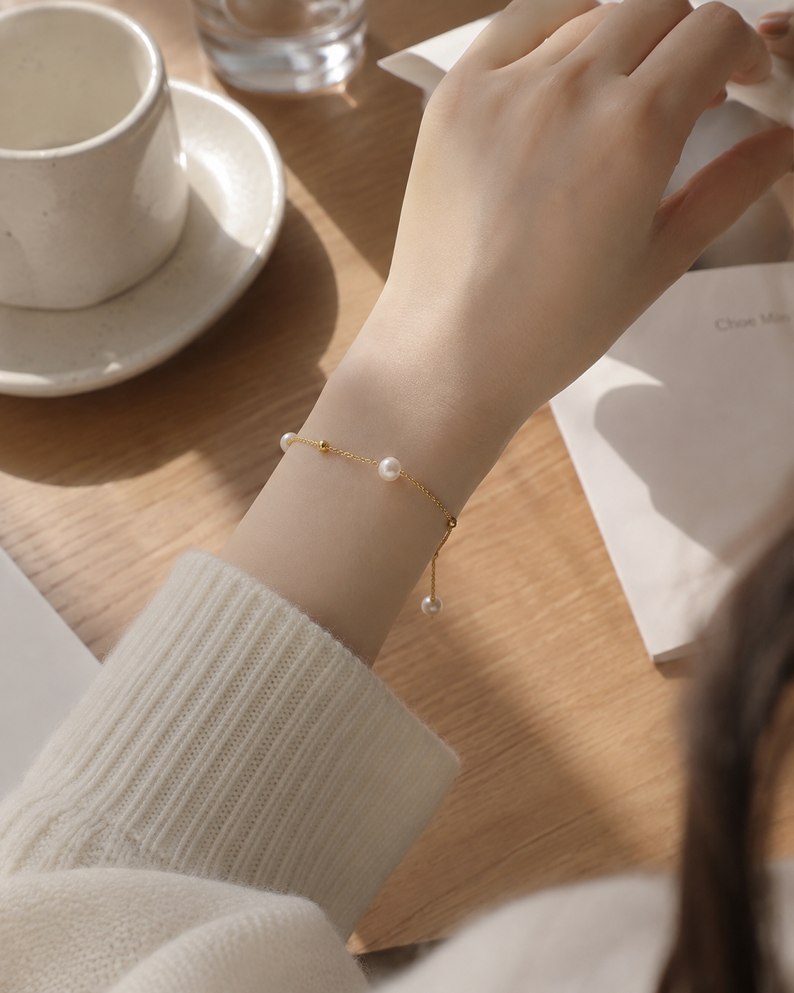 Delicate gold-tone chain bracelet with white pearls and an adjustable sliding closure