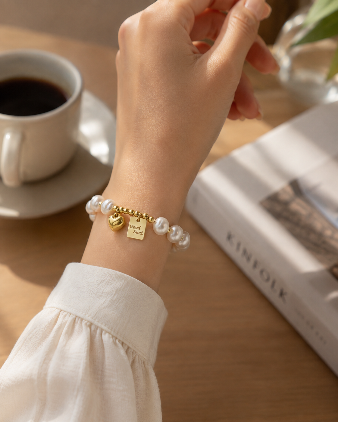White pearl stretch bracelet featuring polished gold-tone beads and two dangling charms