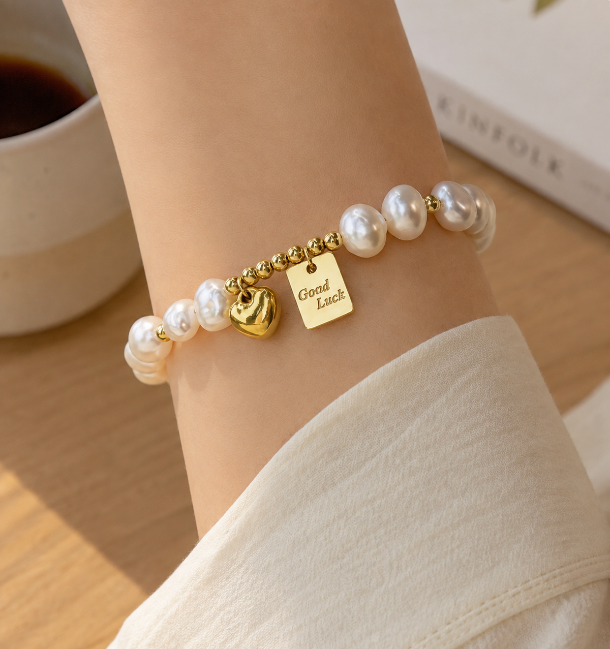 White pearl stretch bracelet with gold-tone beads, a heart charm and a Good Luck pendant