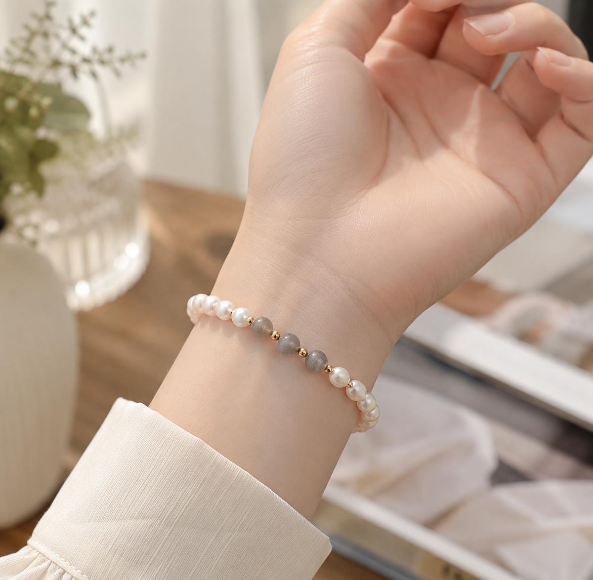 Close-up of a white pearl bracelet with centered gray beads worn on the wrist