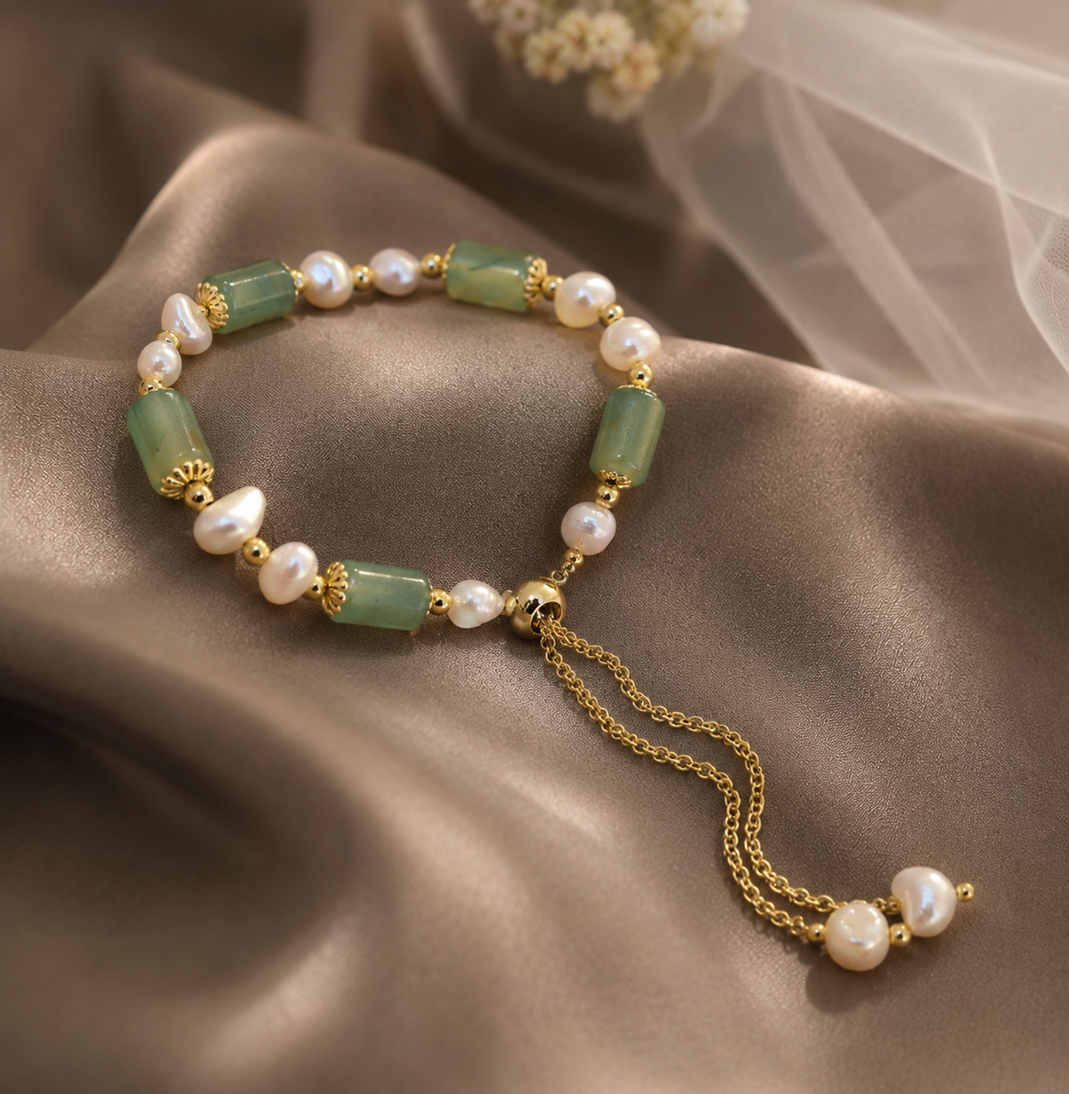 Close-up of a white freshwater pearl bracelet with green beads, gold-tone details and dangling pearl drops