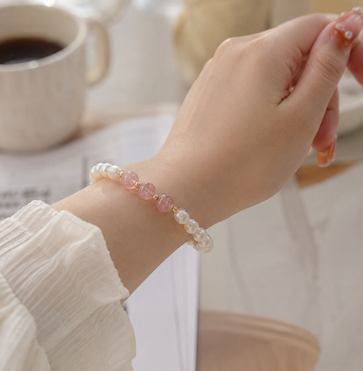 Close-up of a white pearl bracelet with centered translucent pink beads worn on the wrist