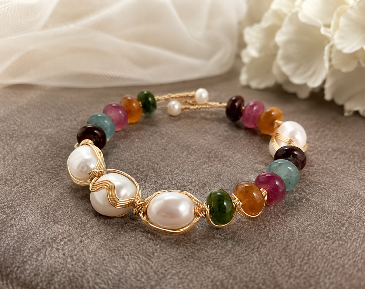 Close-up of white baroque freshwater pearls wrapped in gold-tone wire with multicolor beads